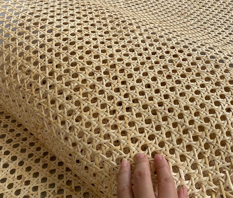 May include: A roll of natural-colored cane webbing with a woven pattern. The webbing is made of thin, light-brown strands, creating a grid-like design. The texture appears smooth and flexible, suitable for various craft projects.