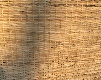 Peut inclure: Un gros plan sur un mur en osier tissé de couleur brun naturel. Le mur est composé de fines bandes de matériau tissé, créant un motif texturé. Le texte "Hoi An Vietnam" est visible dans le coin inférieur droit de l'image.