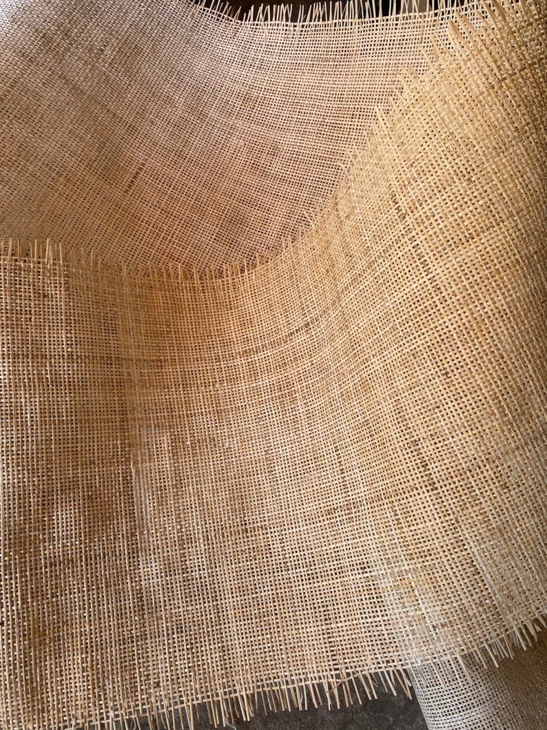 May include: A close-up of a natural brown burlap fabric with a woven texture. The fabric is folded and has a frayed edge.
