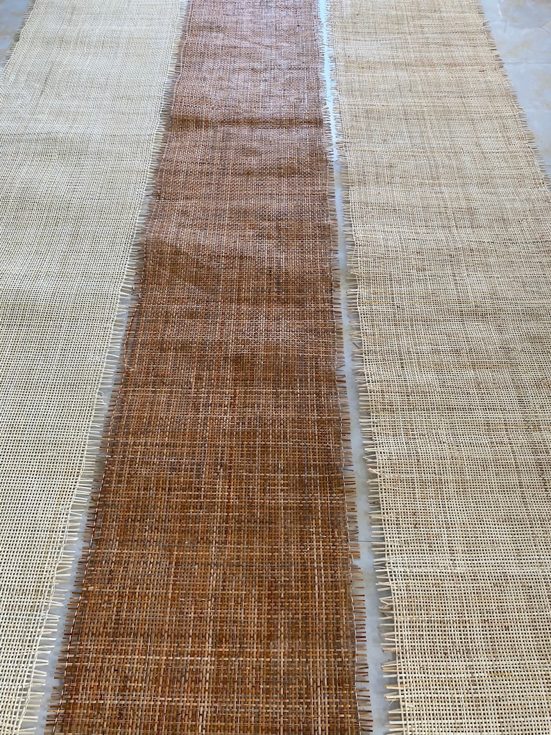 May include: Three strips of woven fabric, one brown, one white, and one beige, laid out side by side. The fabric has a woven texture and is likely used for crafting.