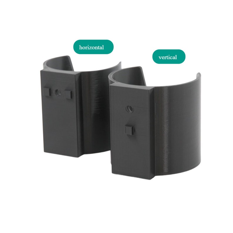 May include: Two black plastic phone holders, one in a horizontal orientation and the other in a vertical orientation. The holders are designed to be mounted on a wall or surface.