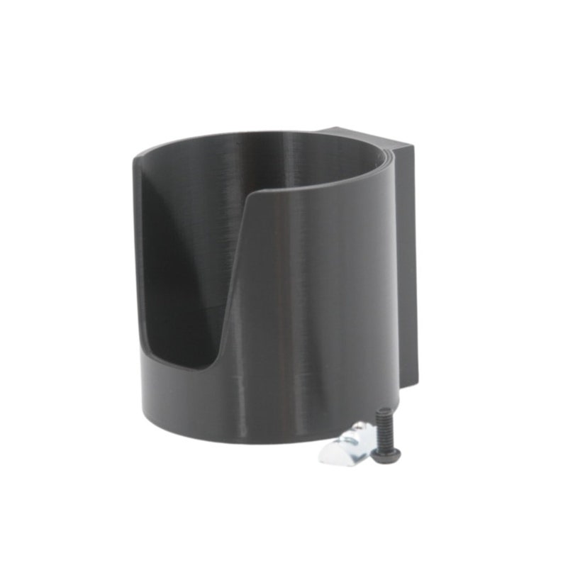 May include: A black plastic cup holder with a mounting bracket and a screw. The cup holder is designed to hold a standard-sized cup or bottle.