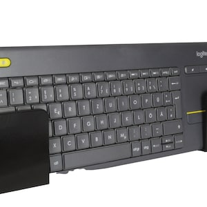 Op de afbeelding: Een zwart toetsenbord met een ingebouwd touchpad en een gele knop linksboven. Het toetsenbord is gemonteerd op een zwarte metalen beugel.