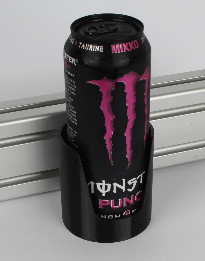 May include: A black can holder with a Monster Energy drink can inside. The can is black with pink Monster claws and the text "Monster Punch" on the front.
