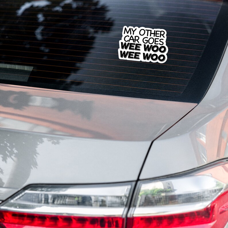 May include: A white car with a sticker on the back window that says "My other car goes wee woo wee woo".