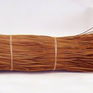 May include: A bundle of long, dried pine needles, tightly bound with three tan rubber bands. The needles are a warm brown color, with a slightly rough texture. The bundle is lying horizontally against a white background.