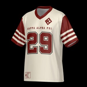 May include: A cream-colored V-neck jersey with maroon sleeves featuring three white stripes. The front displays the text KAPPA ALPHA PSI, the number 29 in large maroon digits, a diamond-shaped logo, and a small rectangular patch at the bottom.