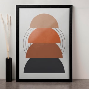 May include: A framed print with an abstract design featuring three stacked semi-circles in shades of brown, orange, and black. The semi-circles are layered on top of each other, creating a geometric pattern.