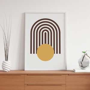May include: A framed print with a minimalist design featuring a brown and white striped arch shape with a yellow circle in the center.