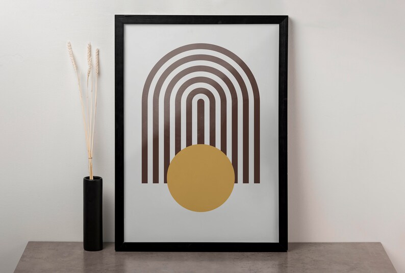 May include: A framed print with a minimalist design featuring a brown and white striped arch shape with a yellow circle in the center.