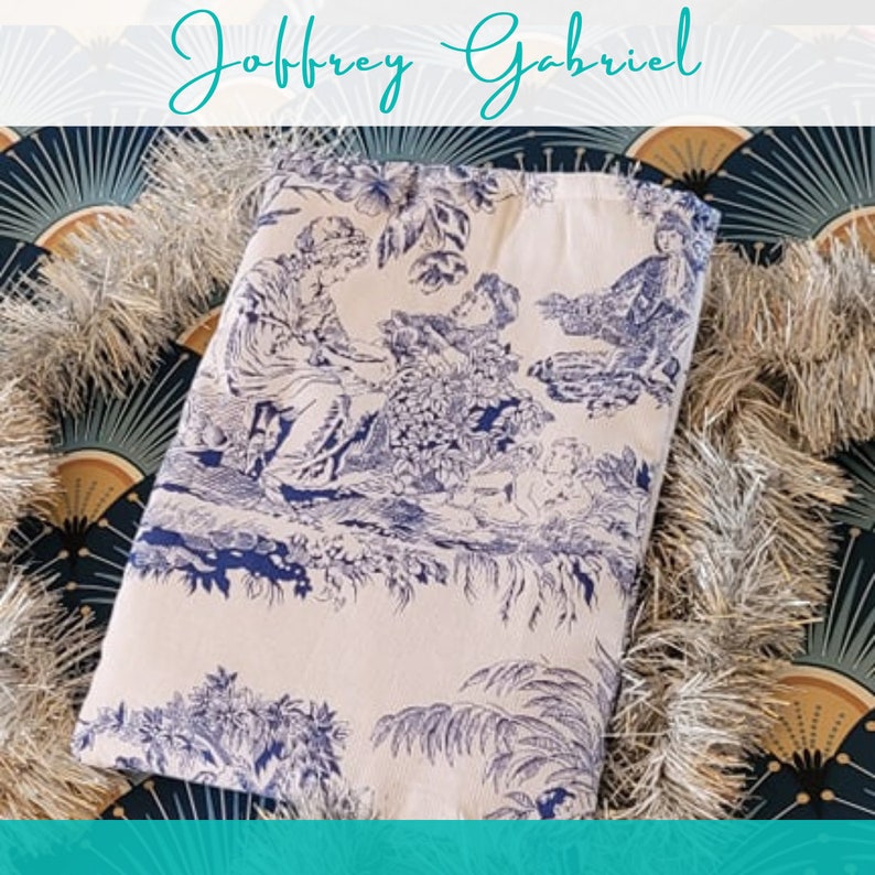 May include: A white fabric tote bag with a blue and white toile pattern featuring a pastoral scene with figures and trees. The bag has a blue trim around the top.