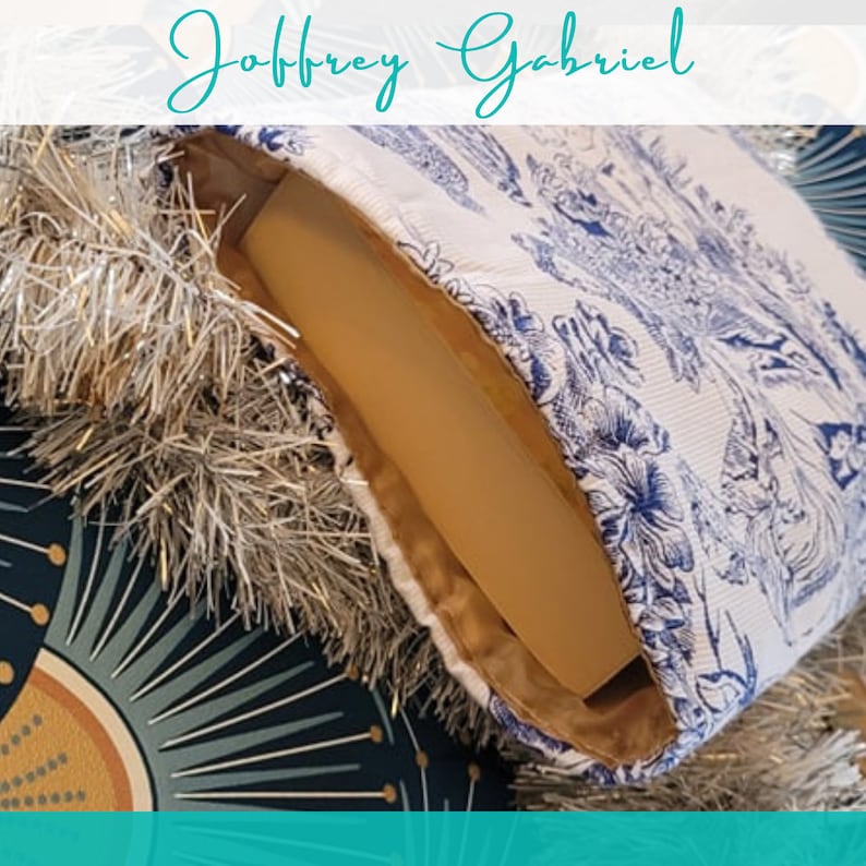 May include: A white stocking with a blue and white floral pattern and a gold lining. The stocking is filled with a gift box and is surrounded by silver tinsel.