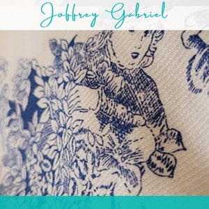 May include: A white fabric with a blue floral pattern. The pattern features a girl in a dress and a floral design.