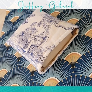 May include: A white book cover with a blue and white floral pattern. The cover is on top of a blue and gold patterned surface.