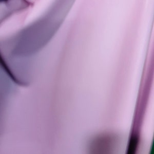 K&ouml;nnte beinhalten: Nahaufnahme eines weichen, glatten, hellvioletten Stoffes. Der Stoff ist gefaltet und hat einen leichten Glanz.