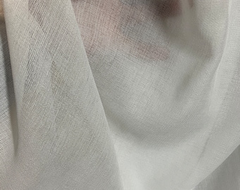 Op de afbeelding: Witte, doorschijnende stof met een fijne, geweven textuur. De stof is gedrapeerd en gevouwen, waardoor zachte, vloeiende lijnen ontstaan.
