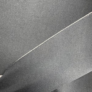 Puede incluir: Primer plano de tela negra con una textura sutil. La tela est&aacute; doblada, creando una costura.