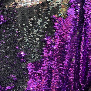 Könnte beinhalten: Nahaufnahme eines Stoffes mit schillernden Pailletten in einem Schwarz-Lila-Farbschema. Die Pailletten sind in einem schuppigen Muster angeordnet.