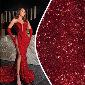 May include: A red sequined evening gown with a plunging neckline and a thigh-high slit. The gown has a fitted bodice and a flowing skirt.