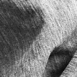 May include: Close-up of a gray, textured fabric with a wrinkled, folded appearance.