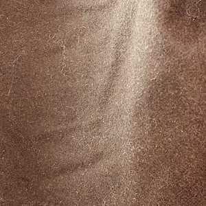 May include: Close-up of a brown fabric with a textured surface. The fabric has a slightly fuzzy appearance.