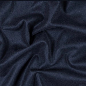 May include: Close-up of a dark blue fabric with a smooth, soft texture. The fabric is folded and draped, creating a sense of depth and dimension.