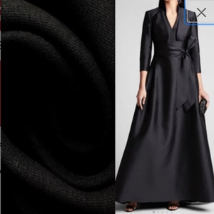 May include: A black long-sleeved dress with a V-neckline and a bow at the waist.