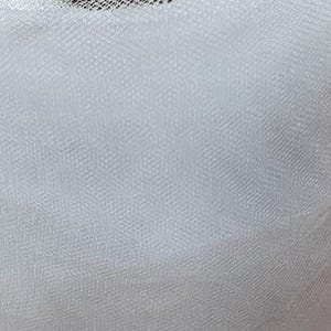 Può includere: Un rotolo di tessuto di tulle bianco. Il tulle è avvolto strettamente, rivelando uno scorcio del nucleo interno di cartone. Il tessuto ha una trama fine e aperta, creando una texture delicata e ariosa.
