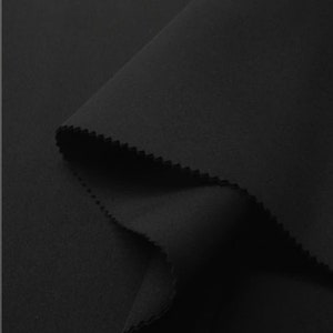 Puede incluir: Tela negra con una textura lisa y uniforme. La tela est&aacute; doblada por la mitad, creando una forma suave y redondeada.