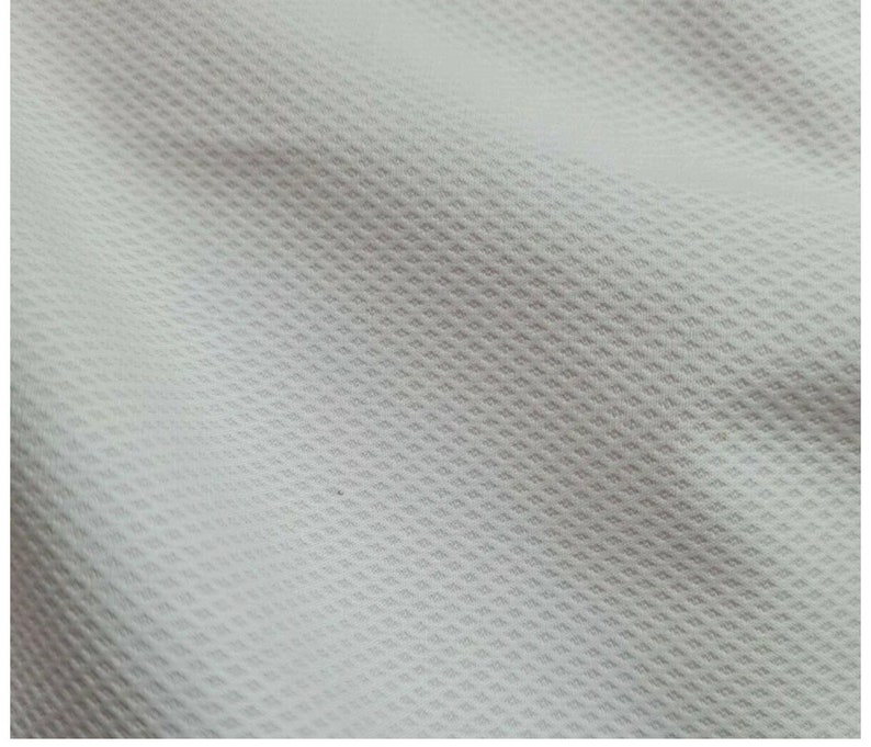 Puede incluir: Tela blanca con un patr&oacute;n tejido texturizado. La tela tiene un tacto suave y liso.