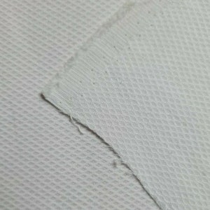 Puede incluir: Tela de malla blanca con un patr&oacute;n texturizado en forma de diamante. La tela es suave y transpirable.