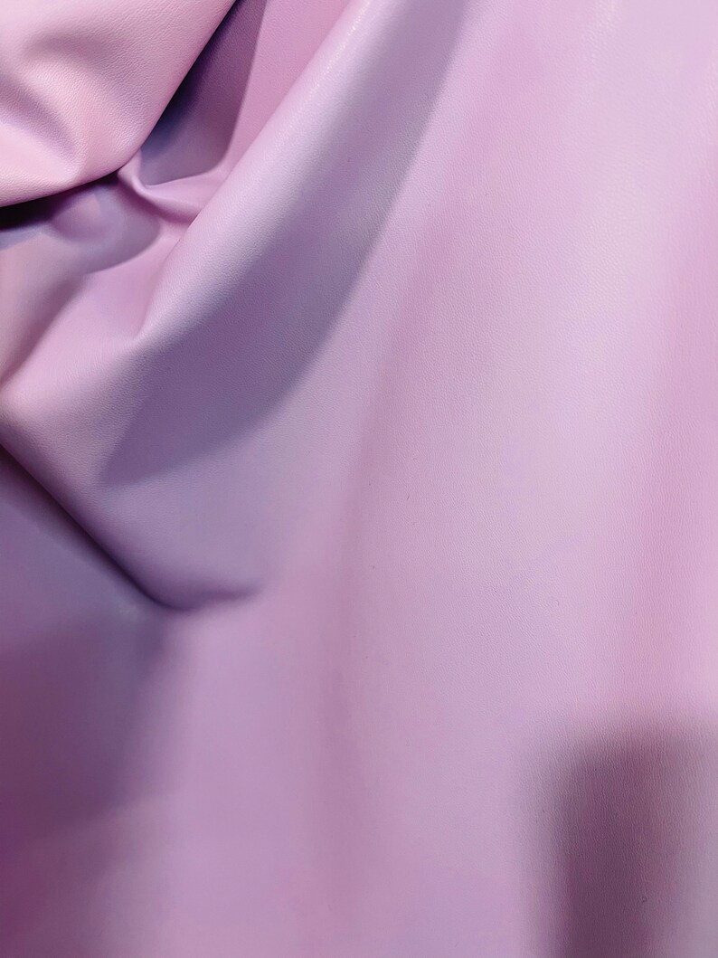 K&ouml;nnte beinhalten: Nahaufnahme eines glatten, weichen, hellvioletten Stoffes. Der Stoff hat einen dezenten Glanz und ist leicht zerknittert.