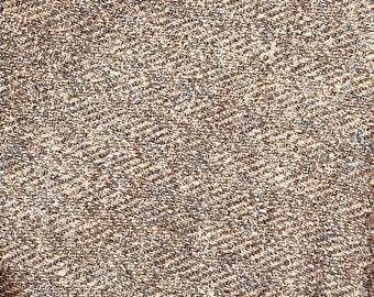 May include: Close-up of a brown and beige textured fabric with a subtle sheen. The fabric has a slightly rough texture and a woven appearance.