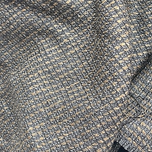May include: Close-up of a textured fabric with a black and brown tweed pattern.