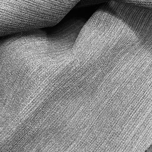 May include: Close-up of a grey textured fabric with a subtle sheen. The fabric is folded and draped, creating soft folds and wrinkles.