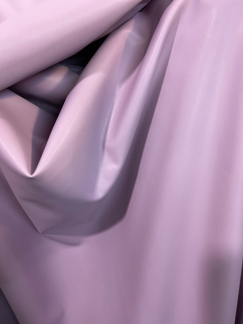 K&ouml;nnte beinhalten: Nahaufnahme eines weichen, glatten, helllila Stoffes. Der Stoff ist gefaltet und drapiert, wodurch seine Textur und Farbe sichtbar werden.
