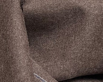 May include: Close-up of a dark brown fabric with a textured surface. The fabric is folded and draped, showing the texture and drape of the material.