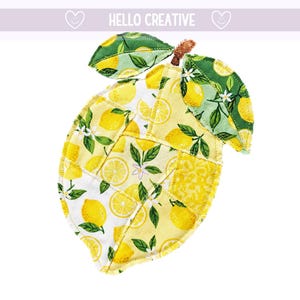 May include: A lemon-shaped fabric item with a patchwork design. The lemon features yellow and white fabric with lemon and floral patterns. Green leaves and a brown stem are attached to the top. The text "HELLO CREATIVE" is at the top.