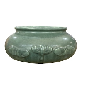 May include: A green ceramic planter with a rounded shape and embossed lotus flower designs.