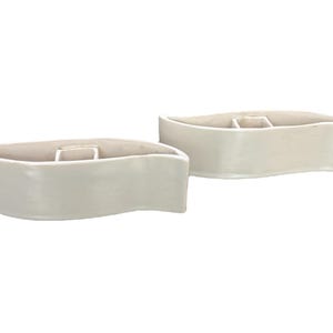 May include: Two white ceramic planters shaped like leaves. The planters are curved and have a smooth, glossy finish.