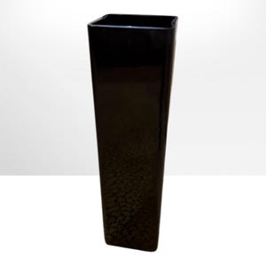 May include: A tall, black, rectangular vase with a textured surface. The vase has a slightly flared shape and a glossy finish. The vase is suitable for displaying flowers or as a decorative accent.