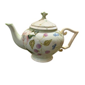 May include: A ceramic teapot with a light green base color, adorned with floral and berry designs in pink, purple, and blue. The teapot features a curved handle and spout, and a matching lid with a decorative finial.