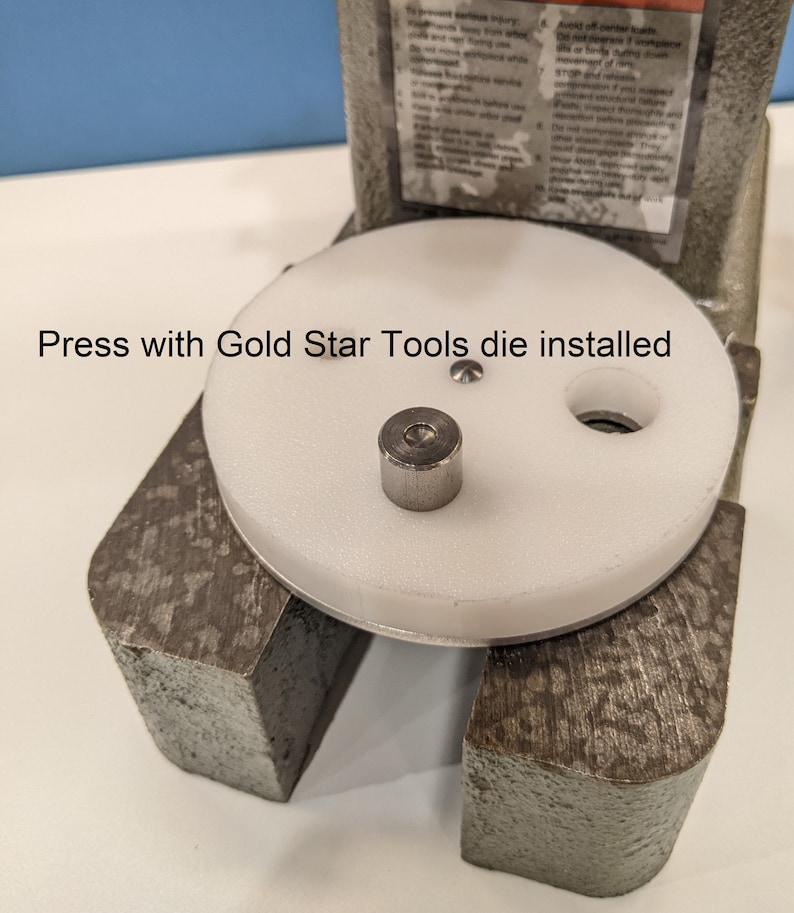 May include: A white press with a round white die and a silver die installed. The press has a gray metal base and a black handle. The text "Press with Gold Star Tools die installed" is visible on the image.