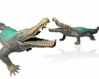 May include: Two bronze crocodile sculptures with open mouths and green accents. The crocodiles are facing each other.