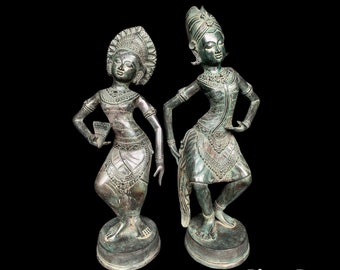 Op de afbeelding: Twee bronzen beelden van dansers, beide met uitgebreide hoofdtooien en traditionele kleding. De beelden zijn in een sierlijke danspose geplaatst.