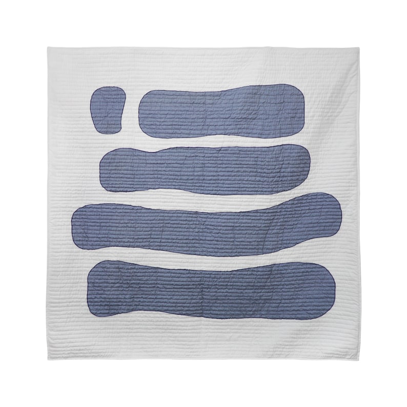 A king-size quilt folded and displayed, showcasing the intricate blue and white appliqué pattern. The quilt is made from cotton fabric and has a soft polyfill batting for added coziness.