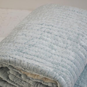 A light blue quilted throw blanket with a soft, textured surface.