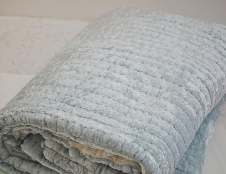A light blue quilted throw blanket with a soft, textured surface.