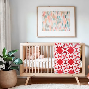 May include: A wooden cot with a white mattress and a red and white geometric patterned quilt. A stuffed toy sits on the mattress. A framed abstract painting hangs on the wall behind the cot.