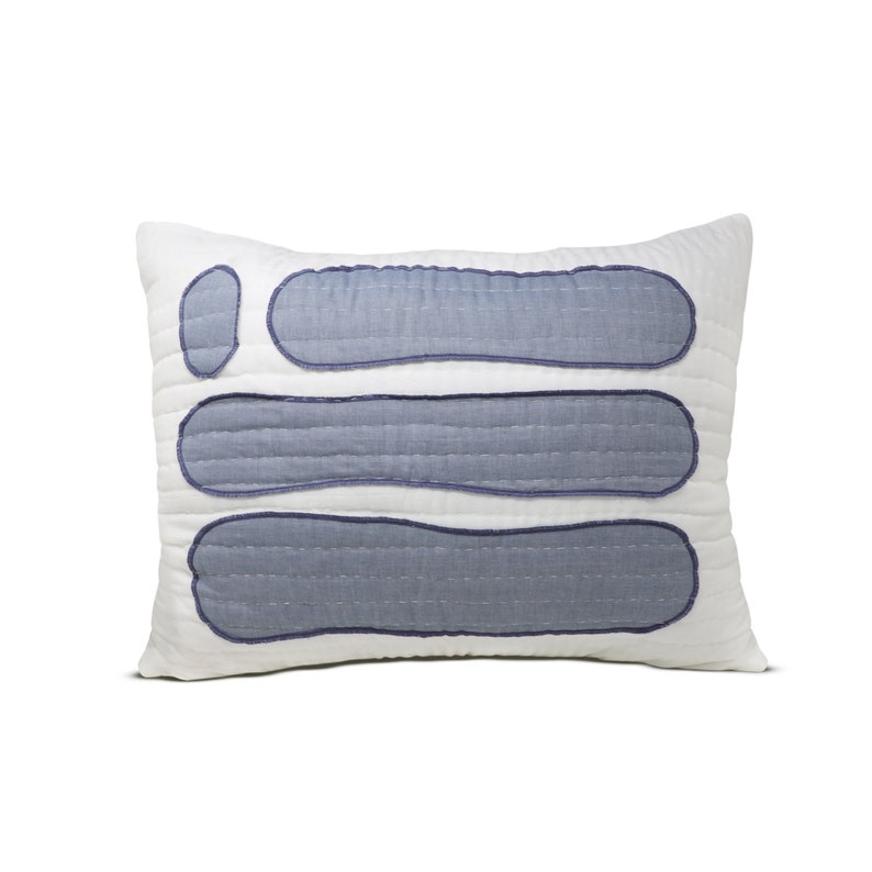 A close-up of a handmade quilted pillow cover with blue cotton fabric appliqué. The cover features intricate hand quilting and is made from soft cotton fabric. The appliqué design is inspired by the famous Stonehenge in the UK.